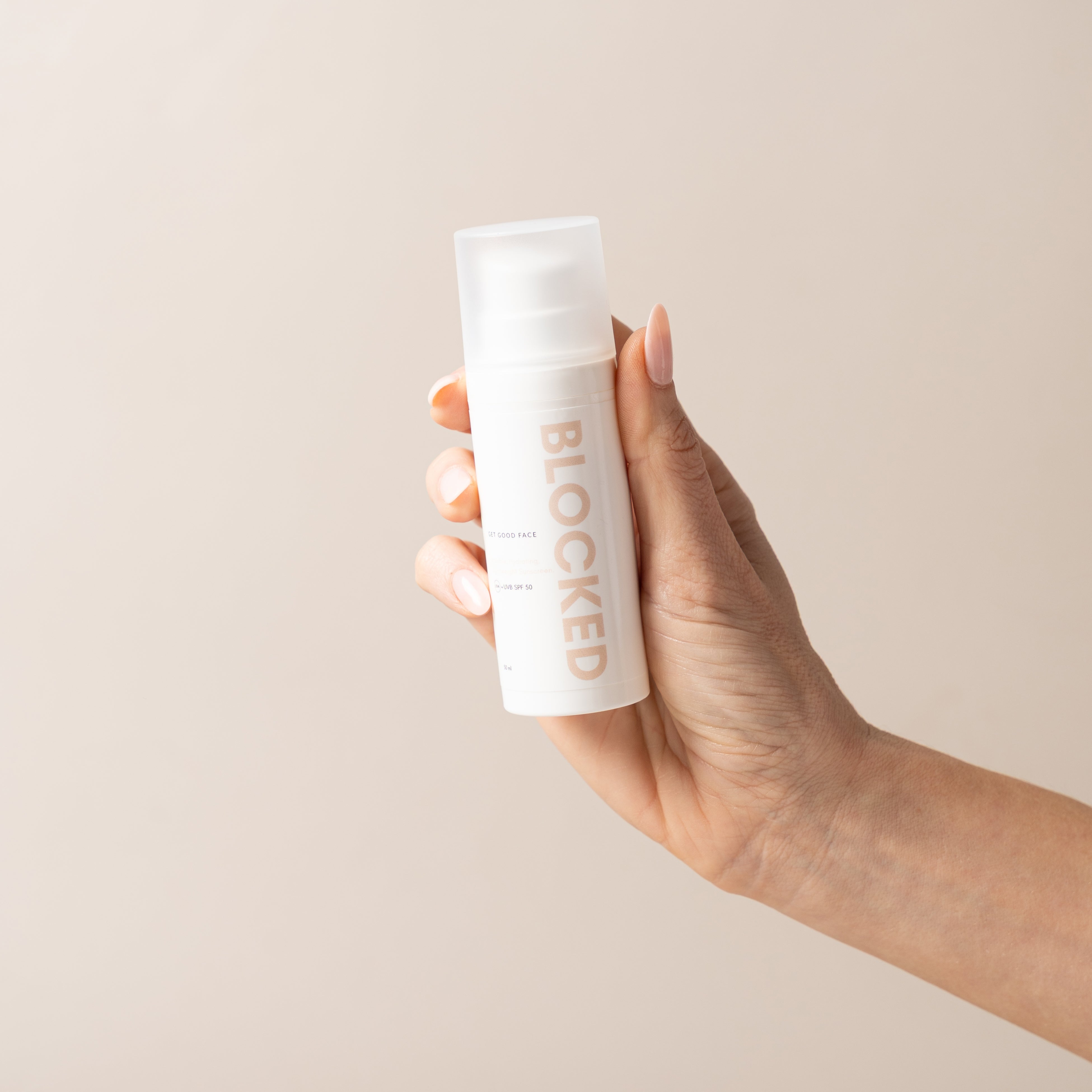 Hand holding skincare bottle labeled "blocked"