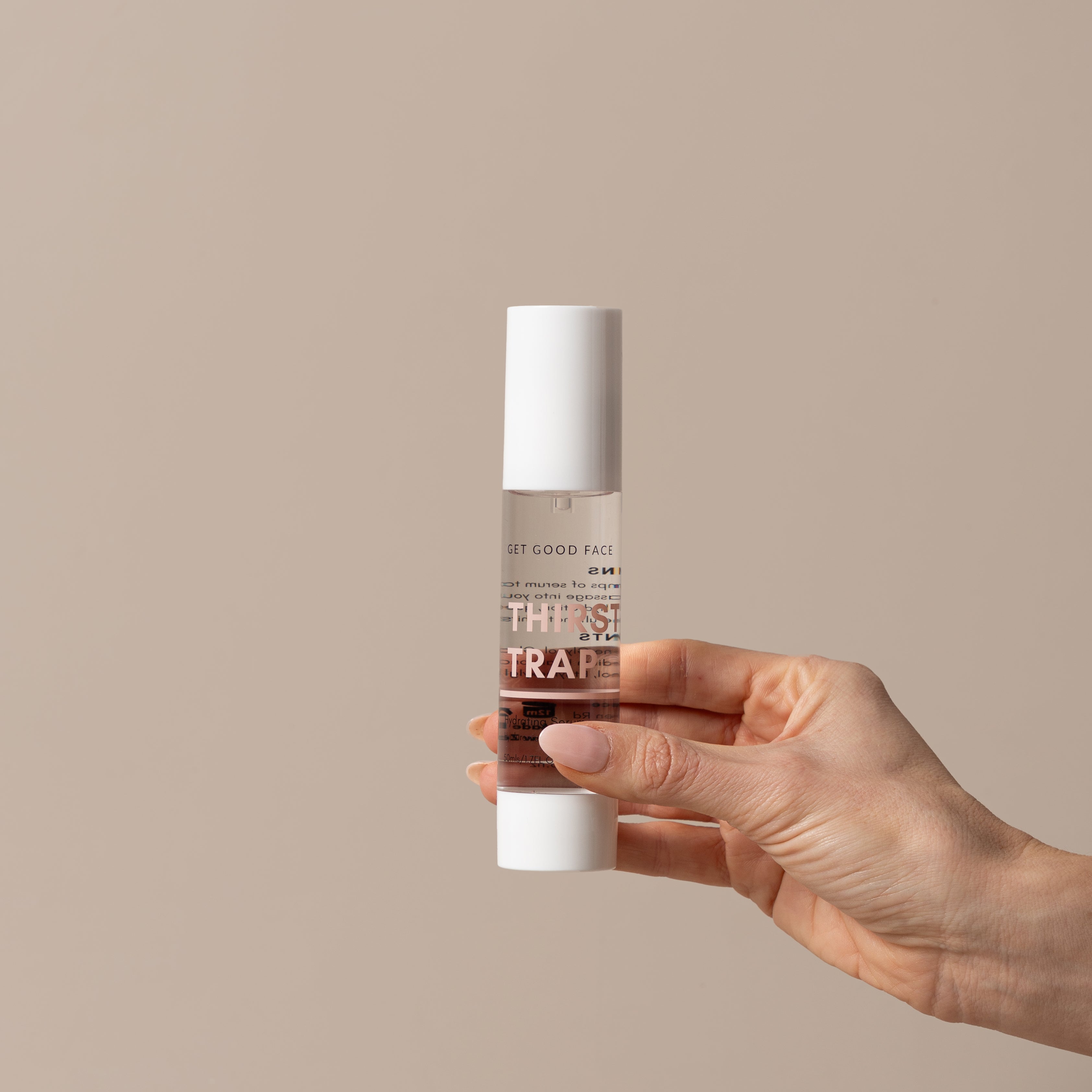 Hand holding a skincare bottle labeled 'THIRST TRAP' against a beige background