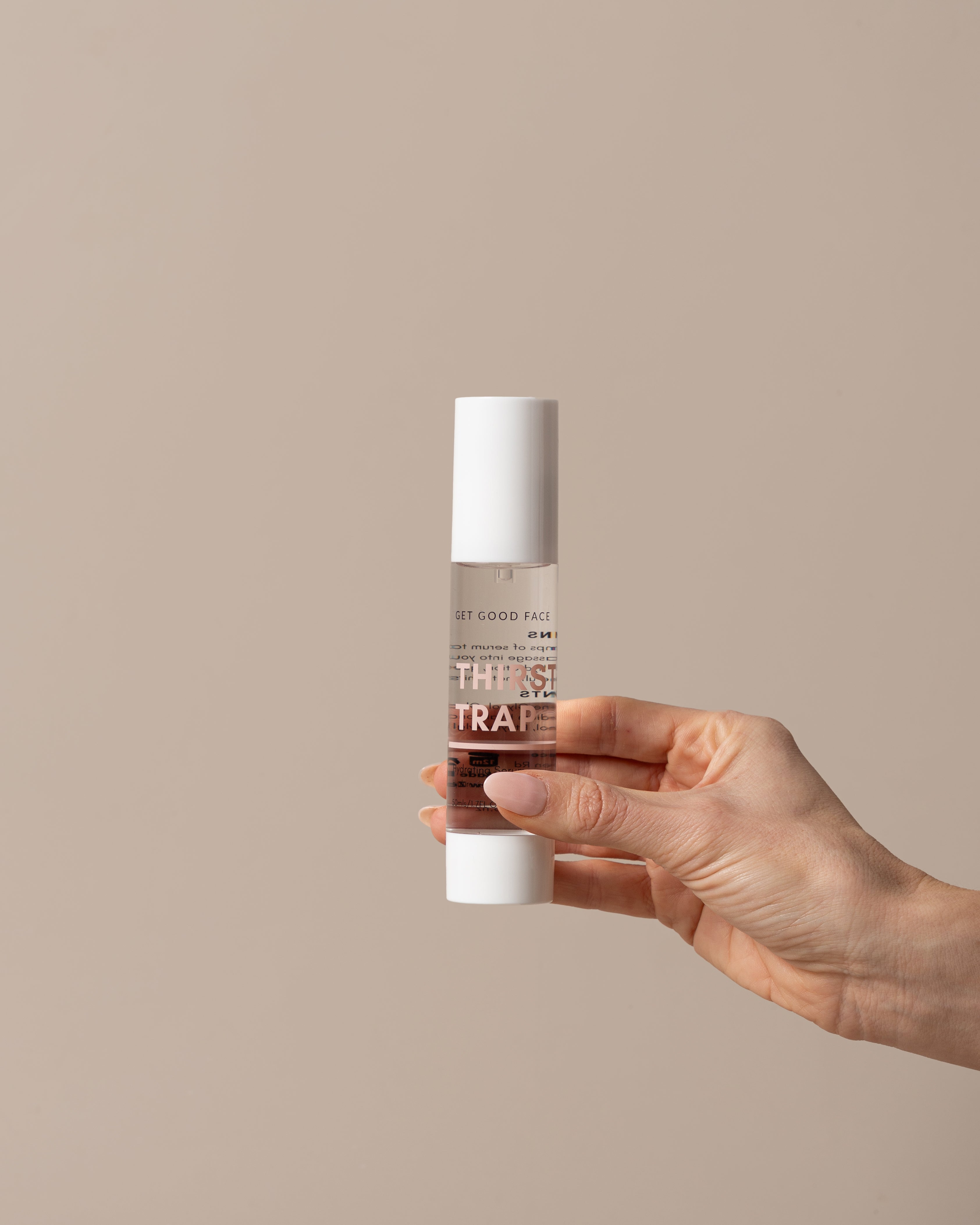 Hand holding a skincare bottle labeled 'THIRST TRAP' against a beige background
